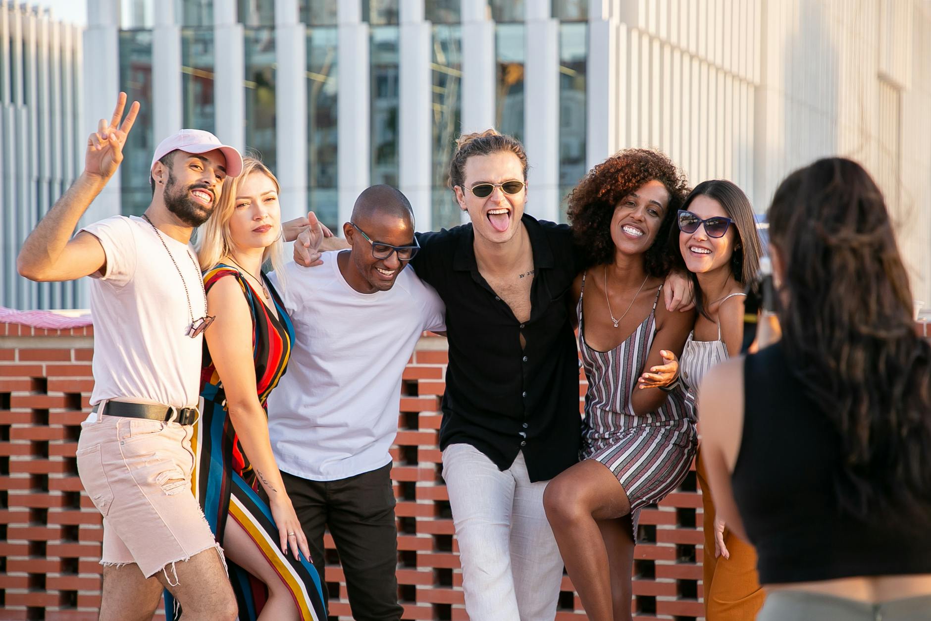 faceless lady taking photo of positive diverse millennials during open air party